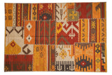 Patchwork Kilim rug with primitive geometric panels, warm earthy tones, and cross-stitch seams.