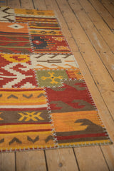 Geometric patchwork Kilim rug detail: varied panels, prominent white cross-stitches, warm palette.
