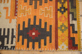 Simulated cross hatch stitches connecting geometric panels of the patchwork kilim rug.