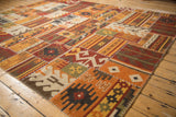 Geometric panel patchwork kilim with white cross-hatch stitches in warm reds and oranges.