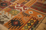 Warm-toned geometric patchwork kilim panels with primitive motifs and white cross-hatch stitches.
