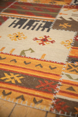 Geometric patchwork kilim panel with saffron yellow, tangerine motifs, and cross-hatch stitching.