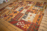 Corner of geometric patchwork kilim featuring warm tones, primitive patterns, and cross hatch stitches.