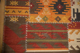 Geometric patchwork kilim detail with brick red finned floral motifs and white cross-stitch seams.