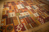 Geometric patchwork kilim panels in warm tones, accented by distinct white cross-stitches.