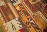 Geometric panels of brick red, saffron, and charcoal on a patchwork kilim rug, with white stitching.