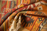 Close-up of handwoven kilim with brick red, ivory geometric panels and white cross-stitch seams.