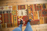 A personal viewpoint looking down at the geometric patchwork and raised stitching of a warm-toned kilim runner.