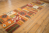 Angled view of a patchwork kilim runner with warm-toned geometric panels and raised stitching.