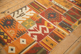 Raised cross-hatch stitches connecting warm-toned geometric panels of a patchwork kilim runner.
