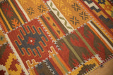 Raised cross-hatch stitches connect geometric and floral panels on a warm-toned kilim runner.