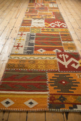 Long perspective view of a patchwork kilim runner highlighting its stitched geometric panels and warm palette.