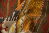 Angled view of a patchwork kilim's simulated seams with raised cross-hatch stitches and geometric patterns.