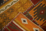 Raised cross-hatch stitches and geometric panels on a folded corner of the warm-toned patchwork kilim.