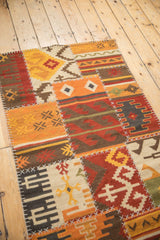 Geometric patchwork panels in brick red, saffron yellow, and ivory with prominent white stitching.