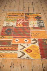 Patchwork Kilim rug corner displays geometric patterns, warm palette, and distinctive cross-hatch stitching.
