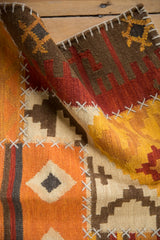 Close-up of vibrant orange, saffron, and brown geometric kilim with raised cross-hatch stitching.