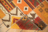 Hand-woven patchwork kilim with white cross-stitch seams on warm geometric panels.