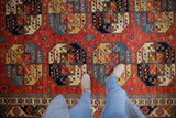 Bold geometric guls and palmettes in cherry red, sapphire blue, and gold hand-knotted pile.