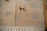 Angled corner view of an Indian carpet showing art silk animals and clean cream fringe.
