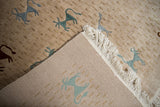 Construction detail of the folk art rug showing the woven foundation, beige pile, and white fringe.