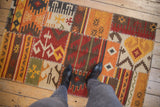 Textured patchwork Kilim rug with warm geometric panels and visible cross-hatch stitching.
