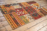 Warm-toned patchwork kilim panel showcasing geometric motifs and prominent cross-hatch stitching.