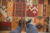 Close-up of a patchwork Kilim rug, showing geometric panels with white cross-stitch seams.