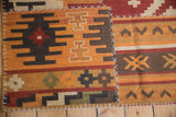 Raised cross-hatch stitches on a geometric patchwork Kilim rug panel in warm tones.