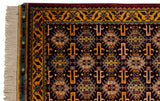 Close-up on the corner of a vintage Indian rug showing the gold vine border and plush navy pile.