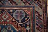 Corner detail of a vintage rug's stepped geometric border and starburst motifs in navy and rust.
