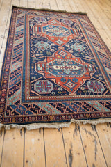 Full length view of a vintage Caucasian style rug, showing the sheen across its geometric medallions.