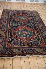 The rich color saturation and lustrous pile of a vintage Caucasian design rug seen from an angle.