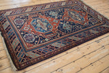 Angled view of a vintage Caucasian design rug highlighting its rich color and lustrous pile.