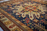 Intricate floral blossoms and geometric motifs in navy, rust, and ivory on vintage Kazak rug.