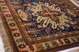 Kazak rug corner shows navy field, stylized turtle motifs on antique ivory border, and fringe.