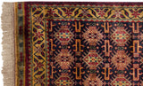 Corner of a vintage Indian rug showing the intact selvage, fringe, and gold starburst floral border.