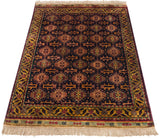 Angled view of a vintage Indian rug showing its lustrous pile and complex Caucasian geometric design.