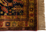 Traditional Indian Kazak rug corner showing navy field, rust-gold floral border, intact selvage, and fringe.