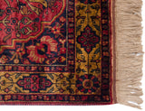 Rich dusty red, navy, gold patterns and ivory fringe on vintage Bakhtiari rug corner.