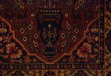 Detailed view of Bakhtiari rug's navy vase, rust field, and rich floral design.