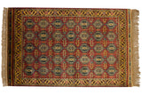 A vintage Indian rug with a Caucasian geometric design in rich wine red, gold, and navy blue tones.