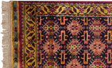 Gold meandering vine border and geometric navy field on a vintage Caucasian design rug corner.
