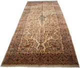Angled view of an oversize vintage Kerman carpet, highlighting its ornate millefleur pattern on an ivory field.