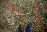 Close-up of vintage Indian Caucasian rug showing elongated floral arabesques in green, blue, and rust tones.
