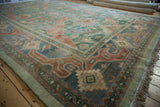 Corner of vintage Indian Caucasian rug, with geometric and floral patterns in green, blue, and coral.