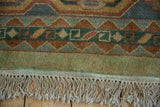 Vintage Indian Caucasian carpet: geometric green, brown, blue pattern, fringed end with green wash.