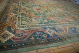 Corner detail of a vintage Indian Caucasian rug's dense pile, showcasing geometric borders in dusty green, denim blue, and coral.