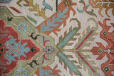 Close-up of vintage Indian carpet's ivory, rust, and seafoam green floral palmettes and laurel leaves.
