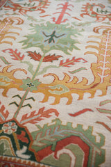 Detailed pile texture of ivory, rust, gold floral palmettes and seafoam green laurel leaves.